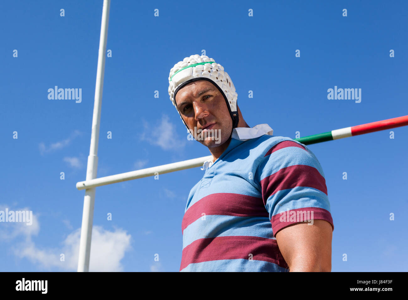 Niedrigen Winkel Porträt des Rugby-Spieler tragen weiße Helm von Torpfosten gegen blauen Himmel Stockfoto