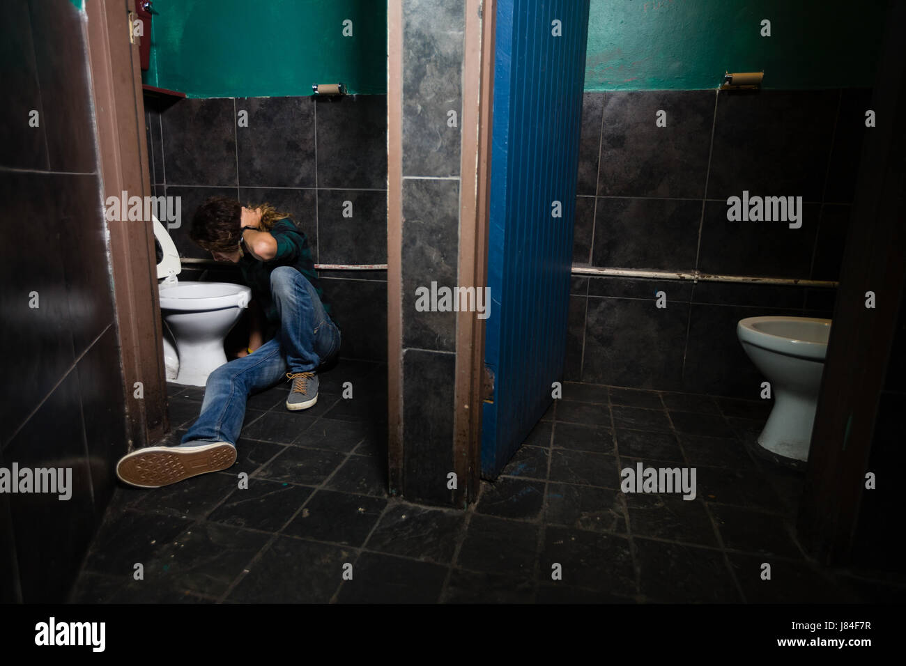 Mann, Erbrechen am Toilettenbecken im Waschraum Stockfoto