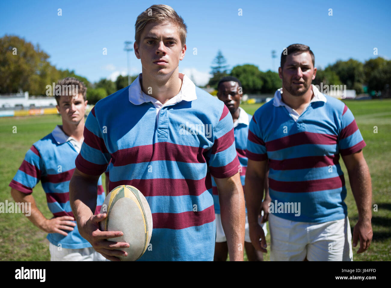 Porträt von zuversichtlich Spieler mit Rugby-Ball auf Feld stehend Stockfoto