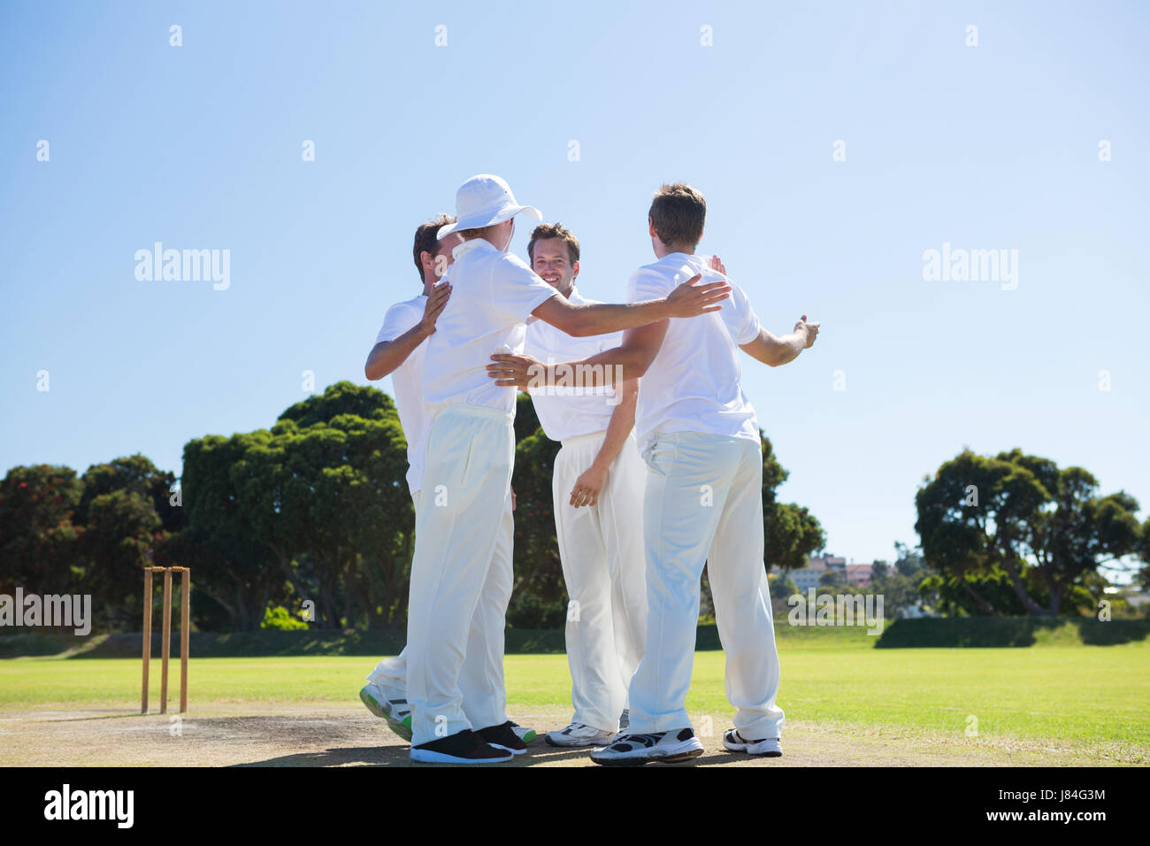 Lächelnde Cricket-Spieler am Feld gegen klaren Himmel stehen Stockfoto