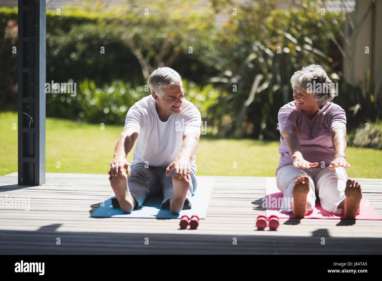 Älteres paar sahen einander während des Trainings zusammen auf Matte zu Veranda Stockfoto