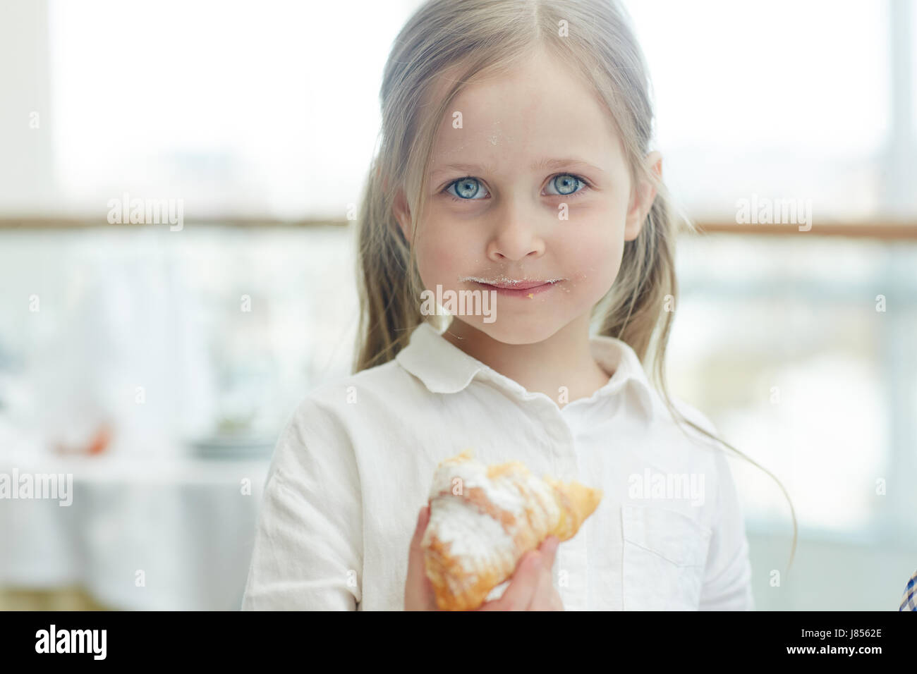 Kleines Mädchen mit Blätterteig, Blick in die Kamera Stockfoto