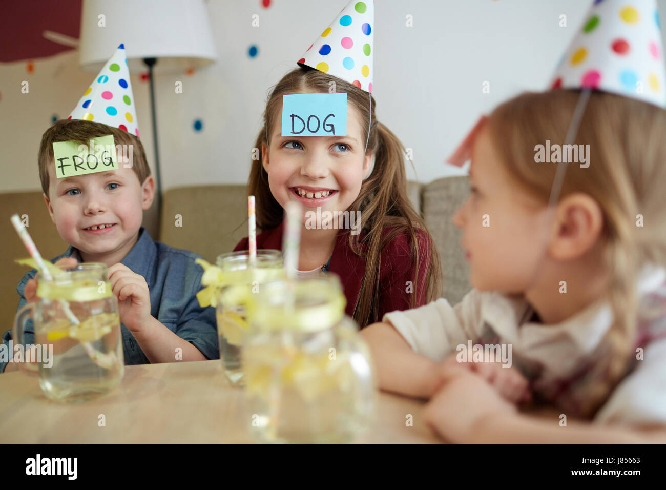 Glückliche Kinder mit Briefpapiere auf Stirnen spielen erraten Spiel Stockfoto