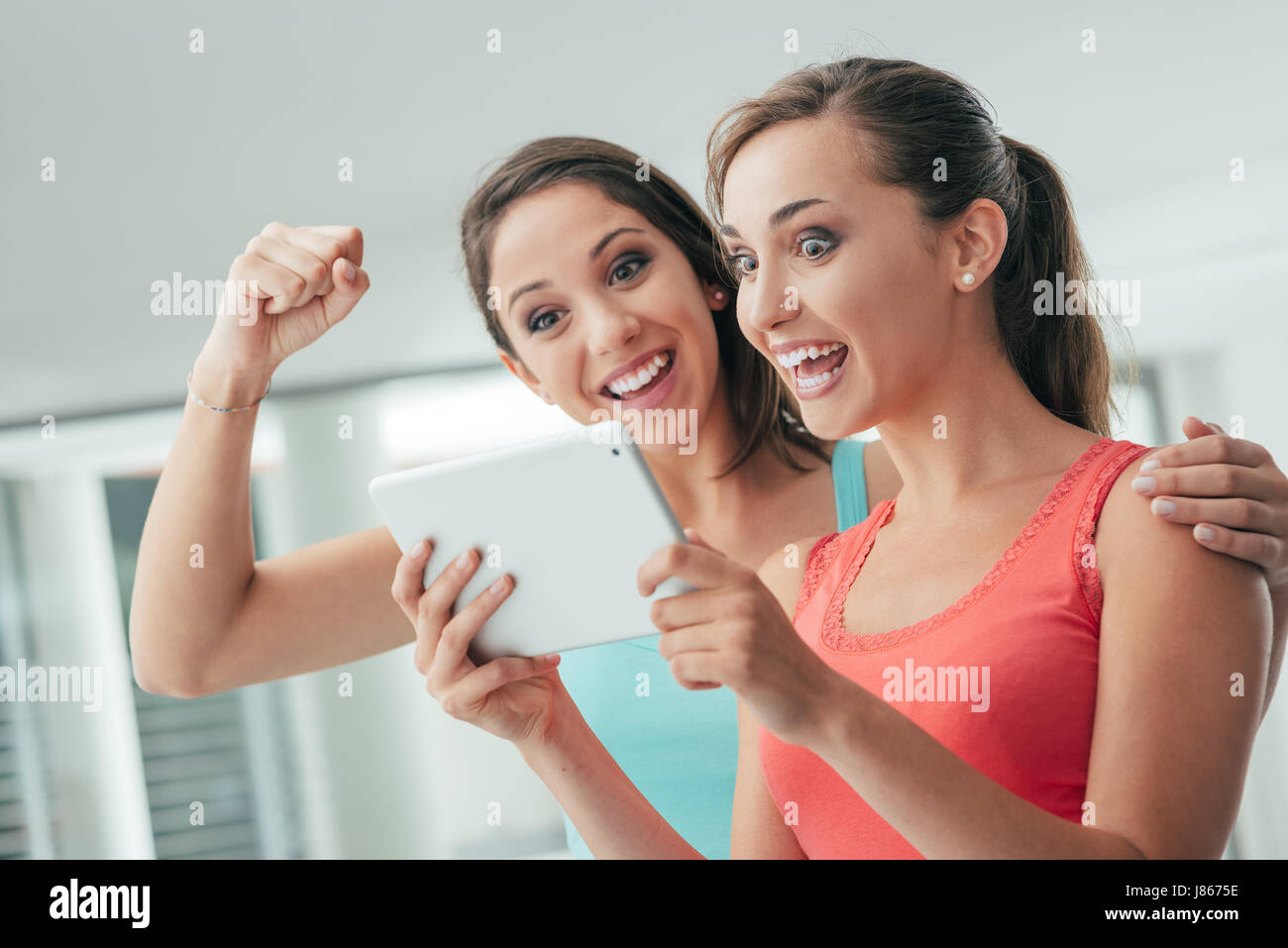 Glücklich Freundinnen Zeit miteinander zu verbringen, steigt Spaß haben und soziale Netzwerke mit einem Touch-Screen-Tablette, eine Faust Stockfoto