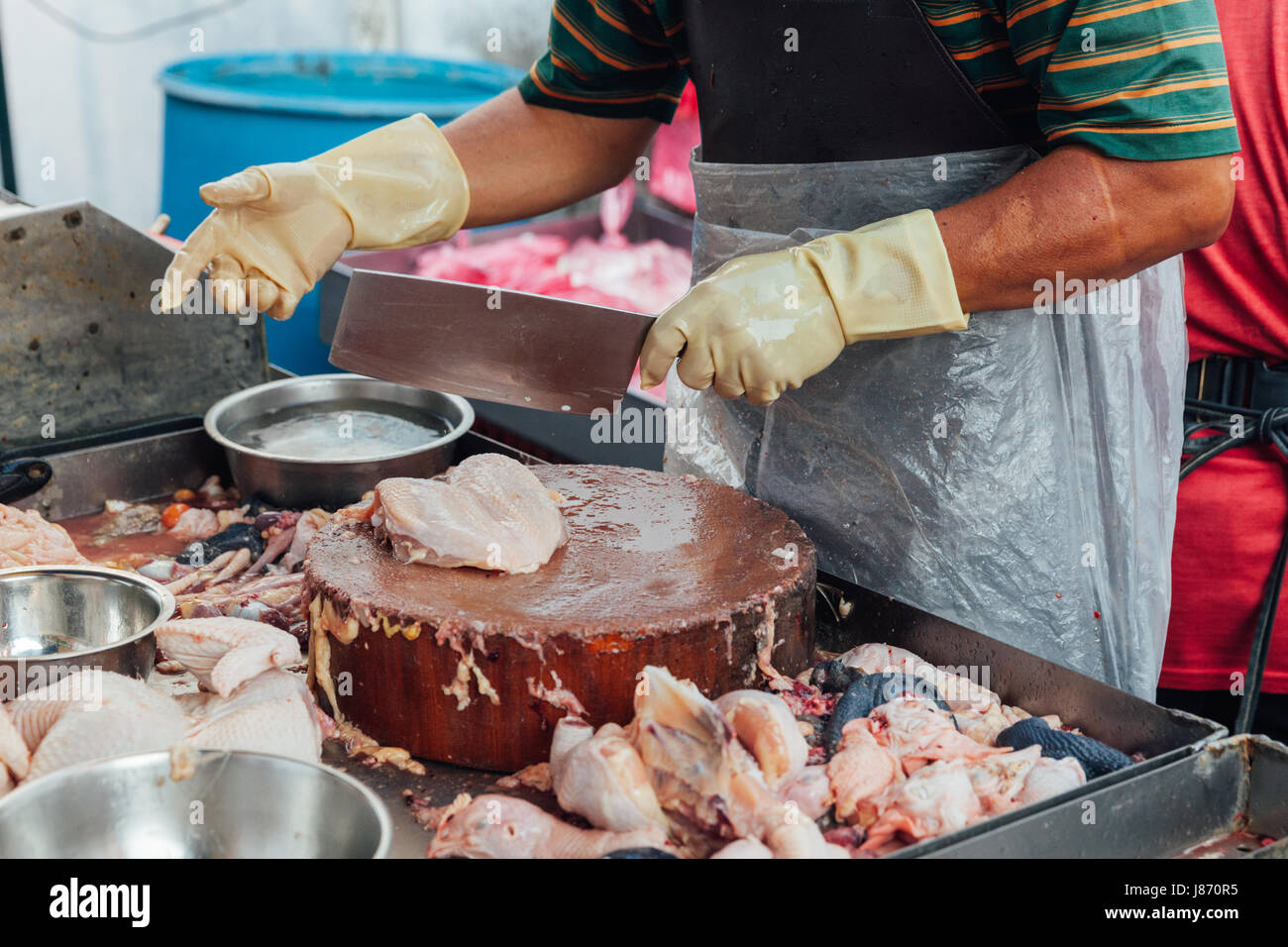 Metzger trennt Stücke von rohem Hühnerfleisch zum Verkauf auf dem nassen Markt von George Town, Penang, Malaysia. Stockfoto