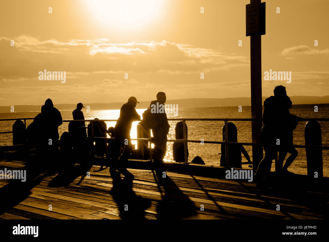 Angler und Touristen auf dem Steg in Cowes, Phillip Island als die Sonne untergeht Stockfoto