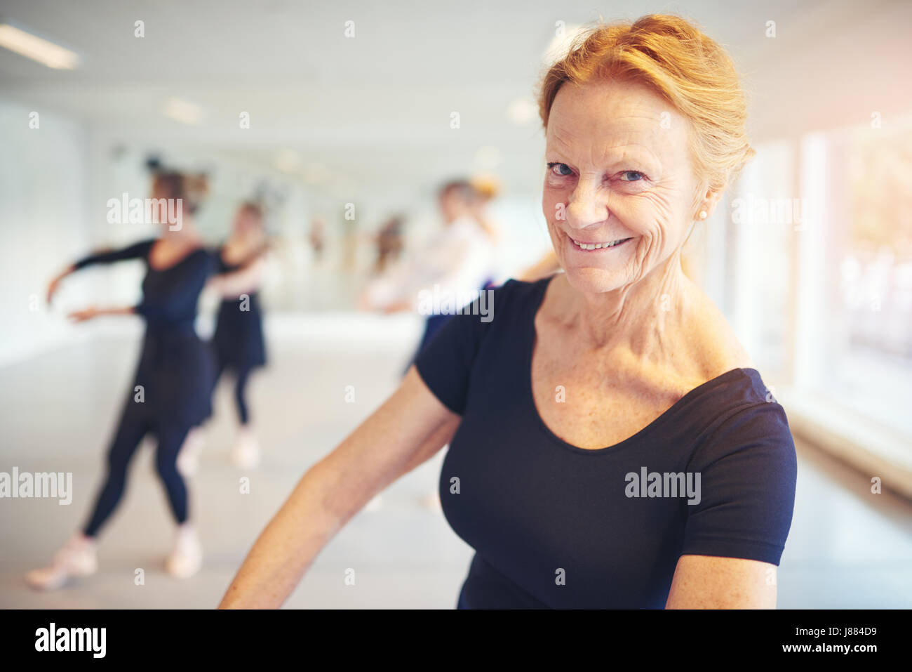 Reife Frau lächelnd und Blick in die Kamera während der Durchführung Ballett in der Klasse. Stockfoto