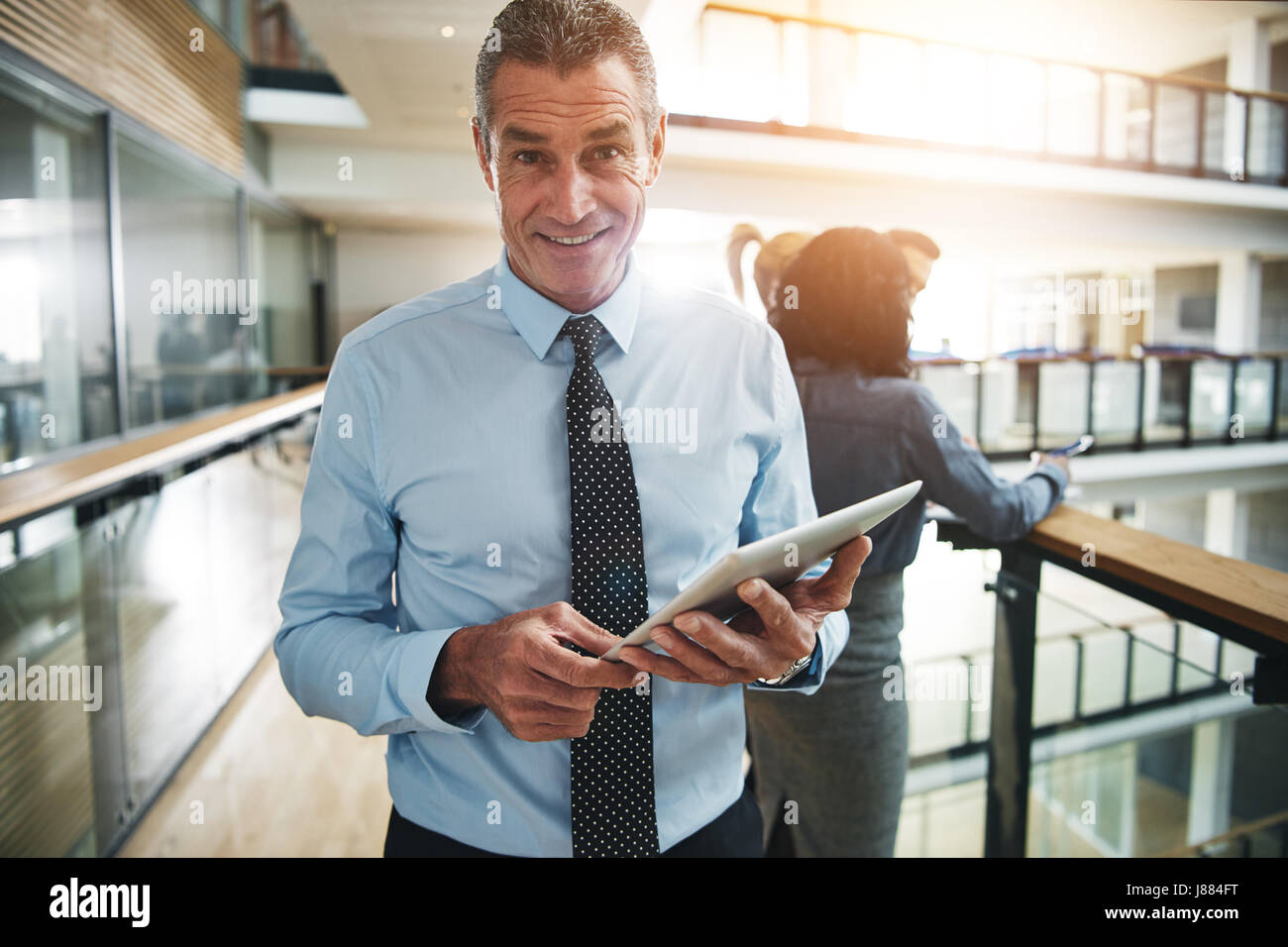 Schöne Reife Büroangestellter stehend mit Tablet und Blick in die Kamera. Stockfoto