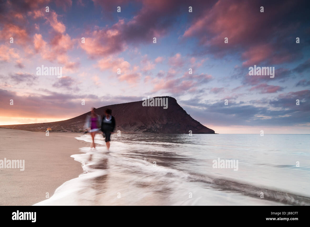 Beach Sunrise auf Teneriffa mit Paar an der Küste und Berg im Hintergrund Stockfoto