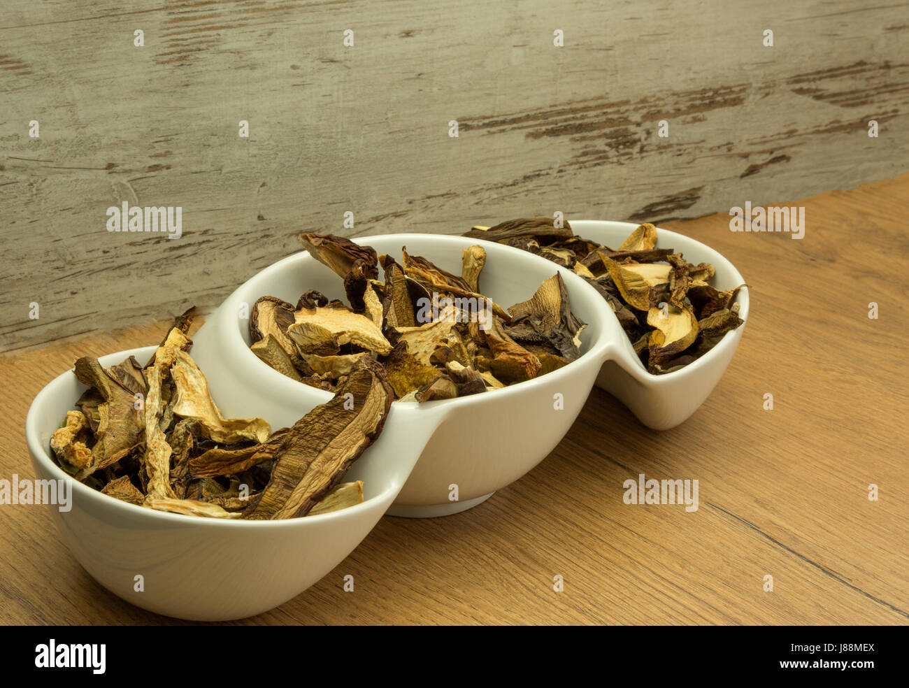 Getrocknet, aromatischen Waldpilzen in einer weißen Schüssel auf einem hölzernen Küchentisch. Ideal für Suppen und verschiedene Gerichte. Horizontale Ansicht. Stockfoto