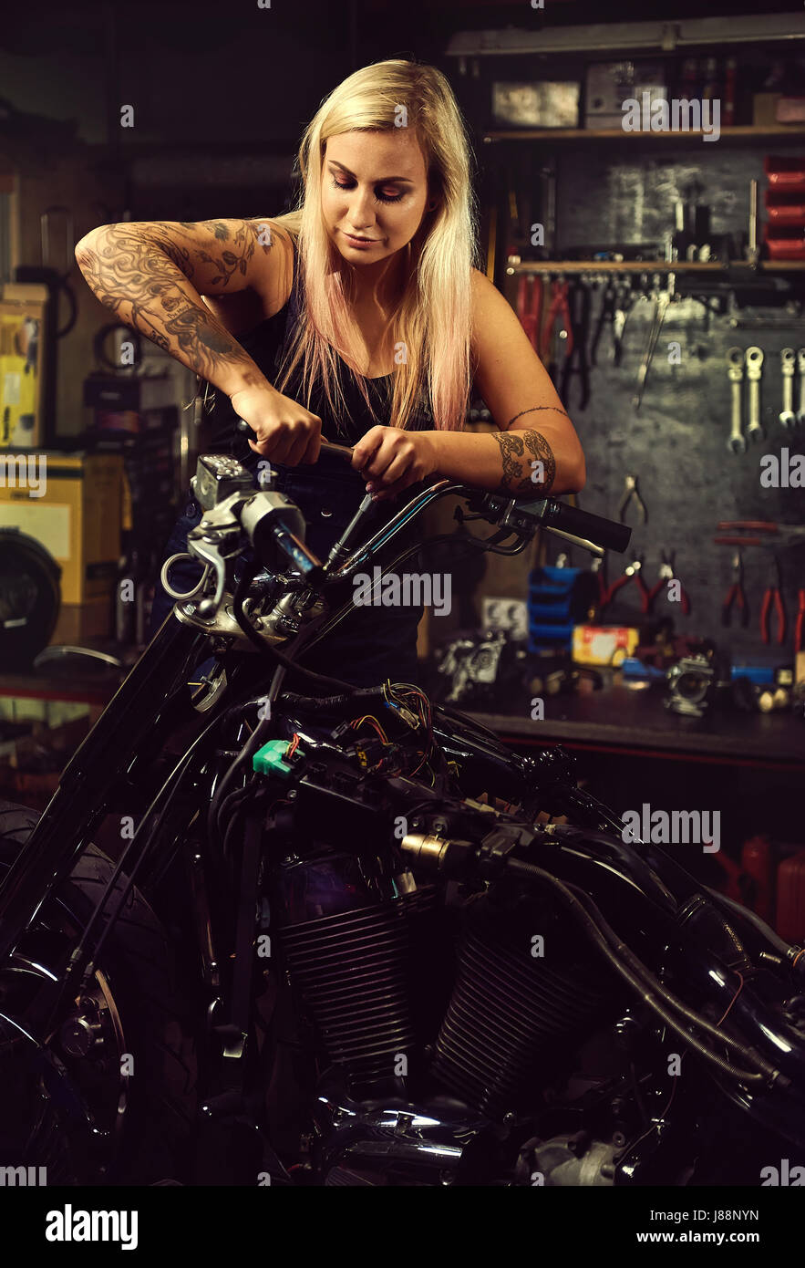 Blonde Frau Mechaniker ein Motorrad in einer Werkstatt reparieren Stockfoto