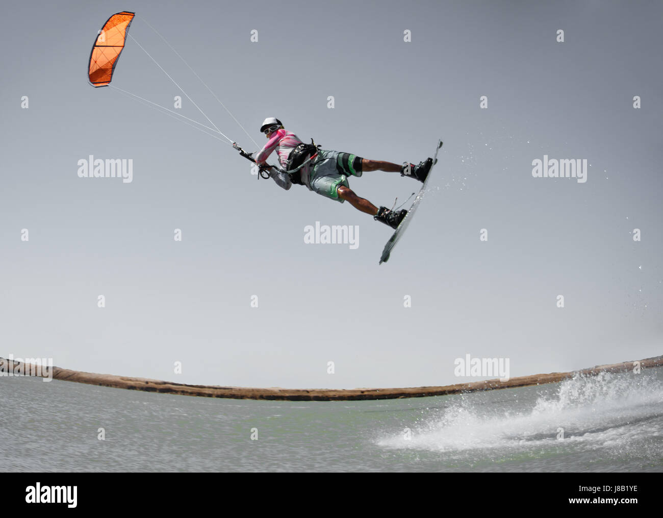 Professionelle Kitesurfen Fahrer Sportler springt hoch Akrobatik Kiteboarding raley Trick mit riesigen Spritzwasser. Freizeitbeschäftigung und extreme Stockfoto