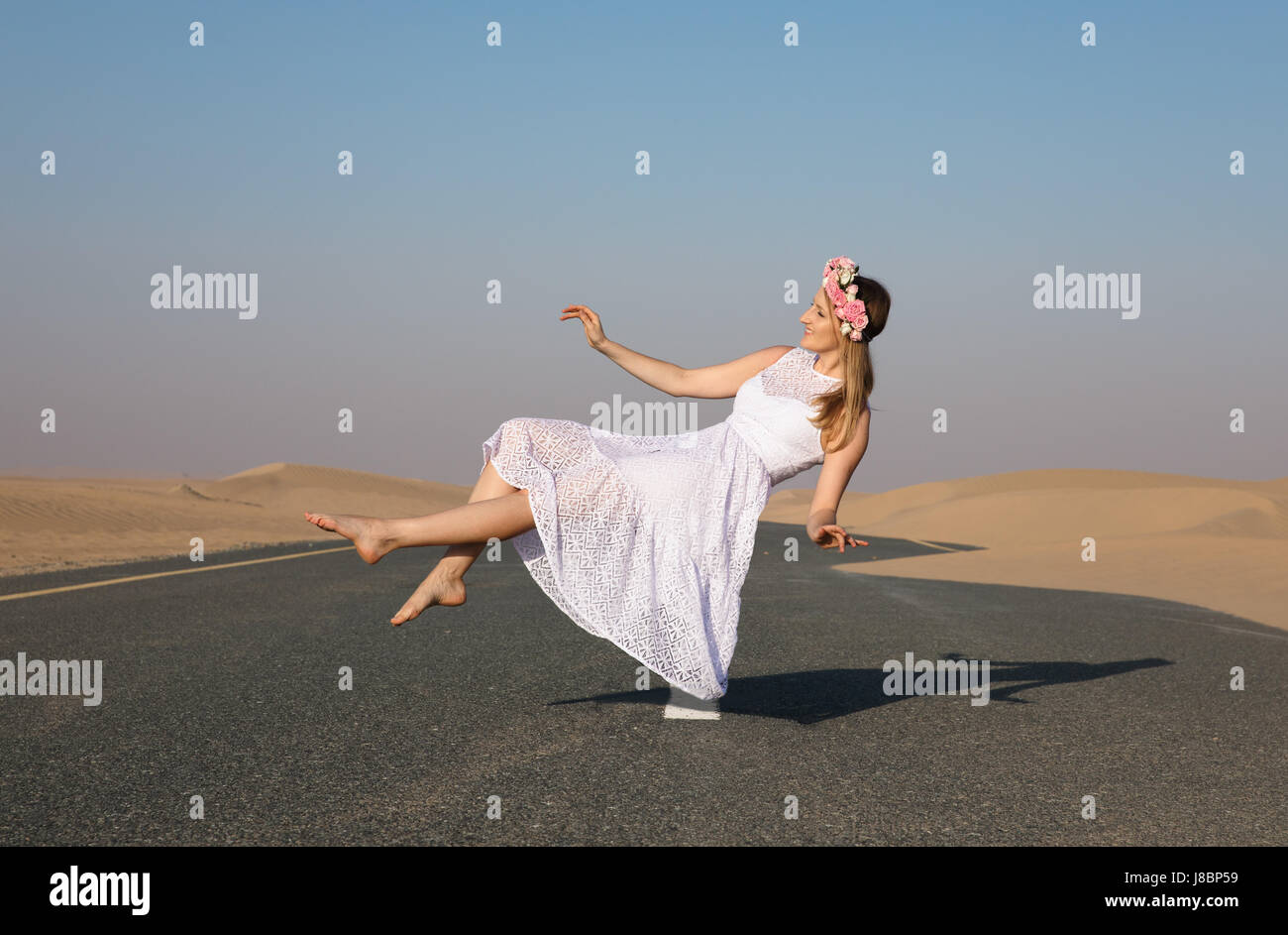 Junge schöne Mädchen mit blonden Haaren und Blume Krone schwebend in der Luft in der Wüste. Stockfoto