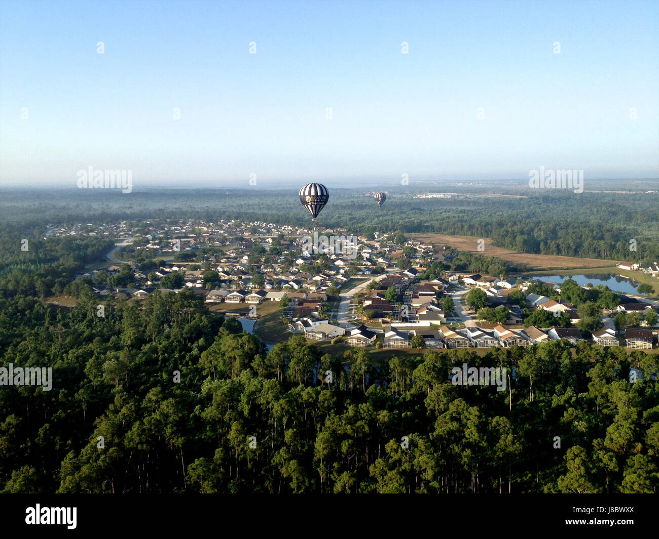 Bild eines Heißluftballons über Florida. Es ist ein sonniger Tag mit einer beeindruckenden Aussicht. Bäume und eine kleine Stadt sind unten Stockfoto