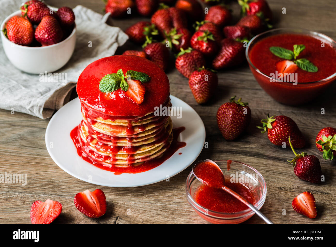 Amerikanische Pfannkuchen und Erdbeersauce und Darm mit einer Beere auf einem hölzernen Hintergrund. Geringe Schärfentiefe. Stockfoto