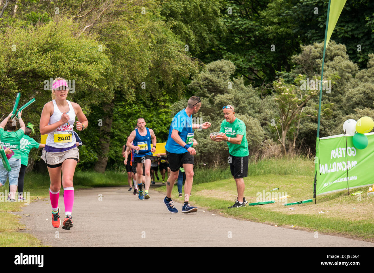 Gosford Estate, East Lothian, Schottland, Großbritannien. 28 Mai, 2017. Eine Läuferin mit rosa Hut und Socken in Edinburgh Marathon Festival 2017 in Gosford Immobilien an der Meile 18 mit einem männlichen Läufer angeboten wird ein süßes an der Macmillan Cancer stand Stockfoto