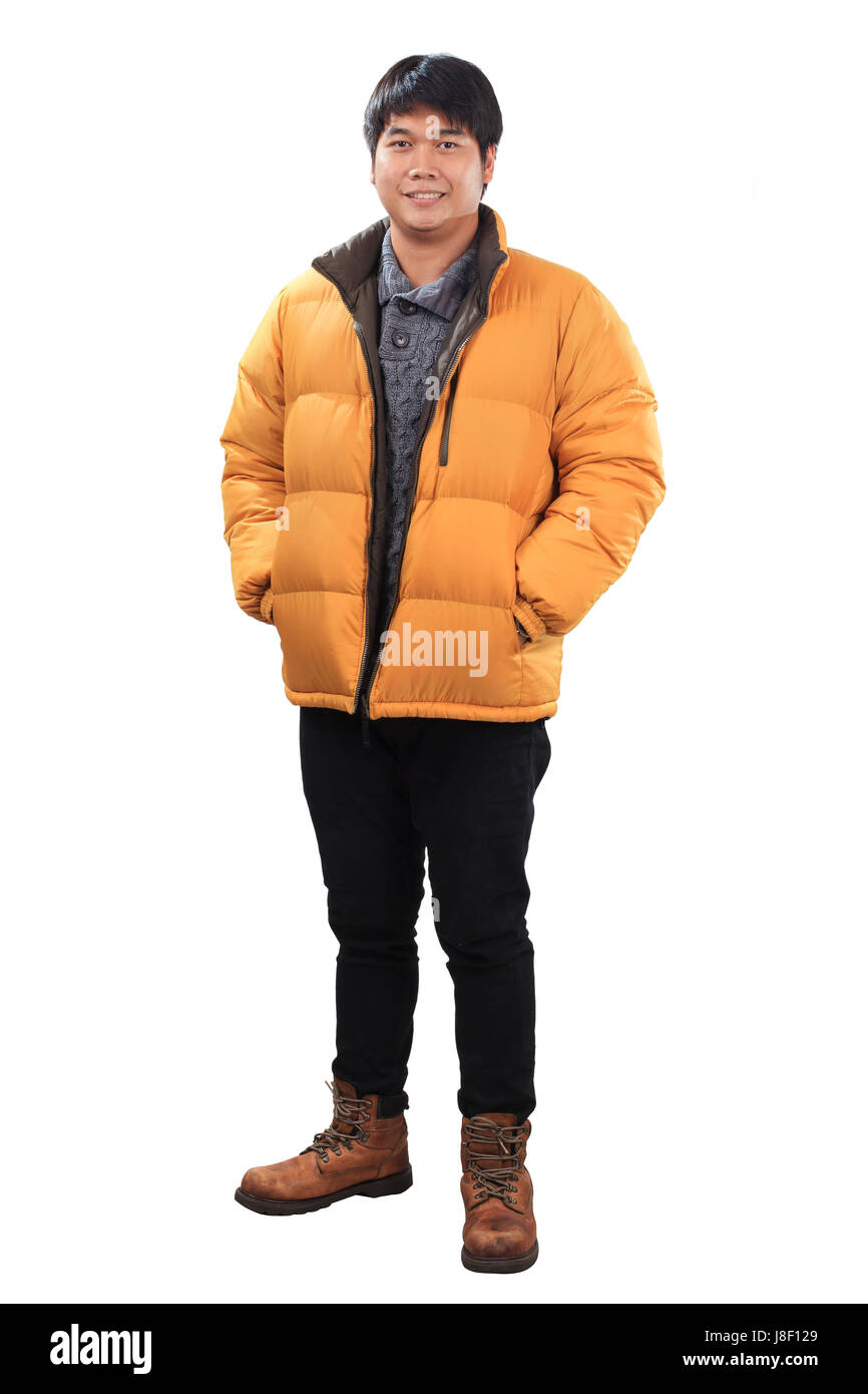 Porträt der jungen asiatischen Mann tragen gelbe Winterjacke und schwarze Jeans Lederschuhe mit lächelnden Gesicht isoliert weißem Hintergrund stehen Stockfoto