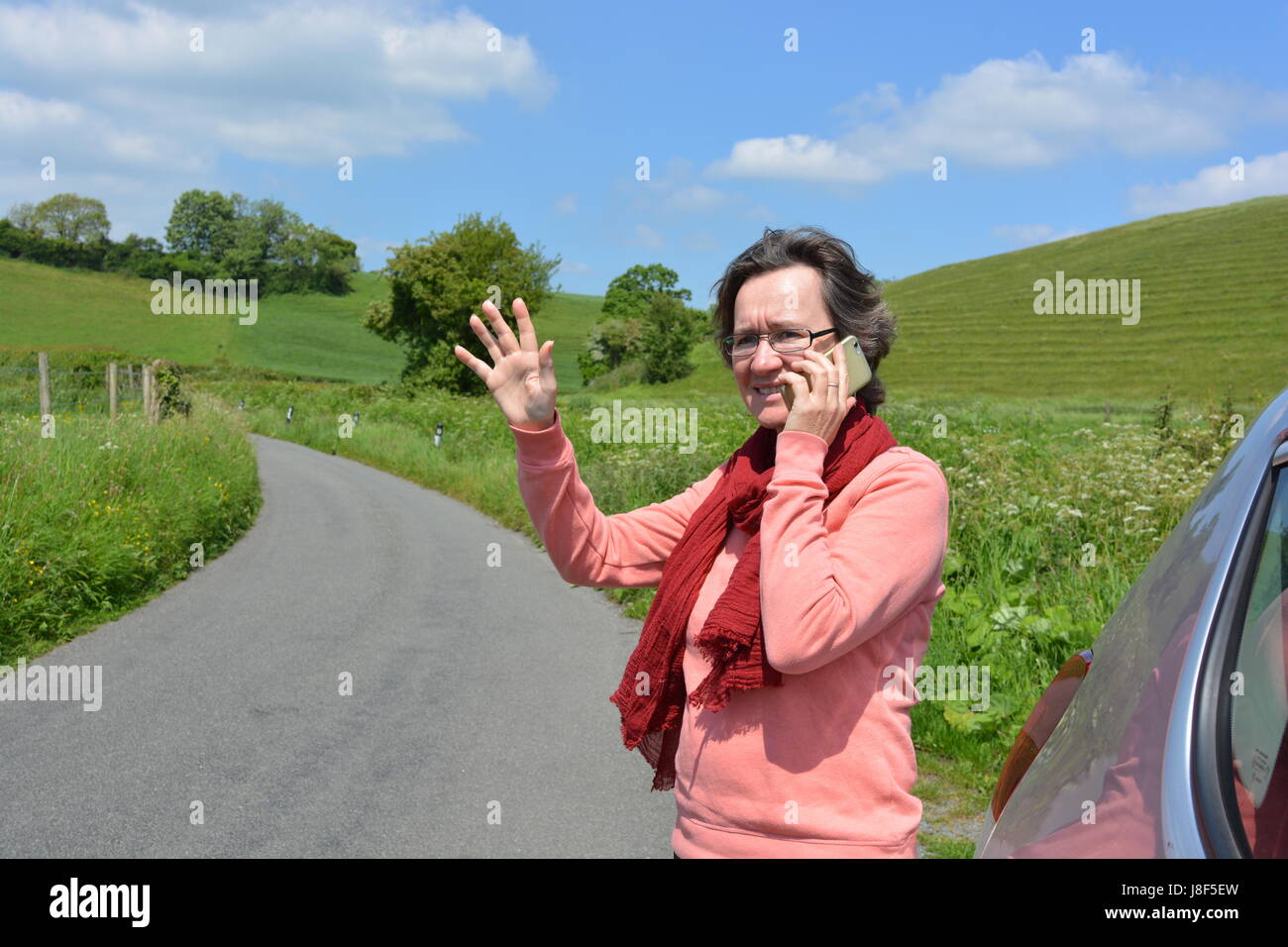 Frau stehend mit dem Briefpapier Auto auf einen Feldweg, Handy Hilfe anfordern Stockfoto