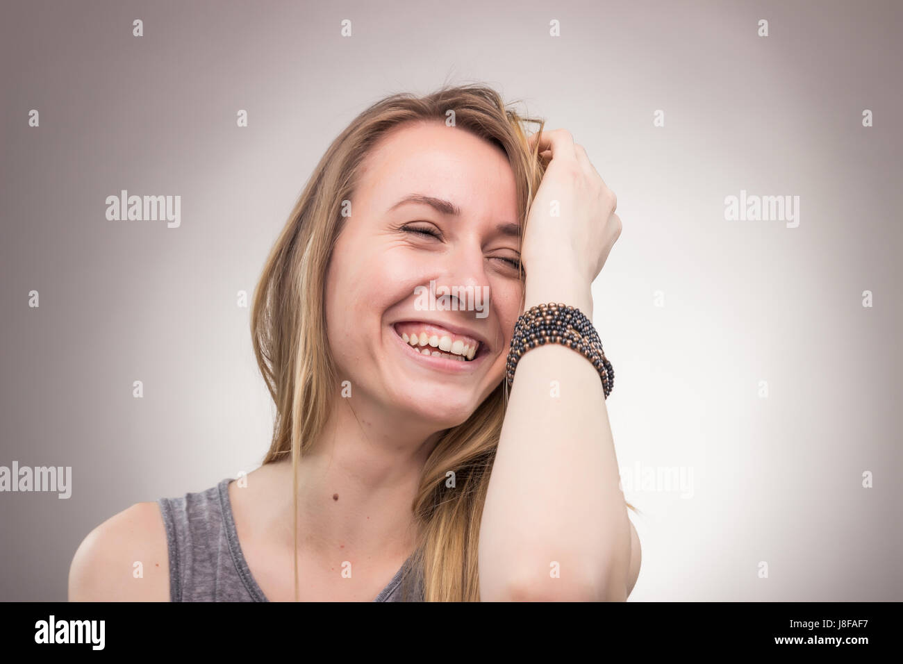 ehrliches Porträt, Lächeln, glücklich, eine junge Erwachsene junge Frau, Studio, Hintergrund Stockfoto