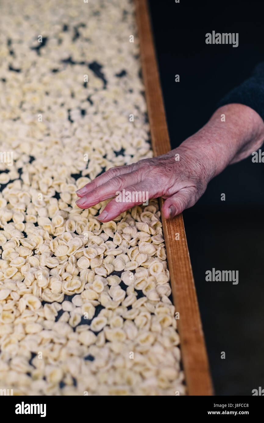 Die Hand von einer älteren Frau neben die traditionellen Orecchiette Nudeln verbrachte sie am Morgen machen von Hand in Bari Vecchia, Apulien, Italien Stockfoto