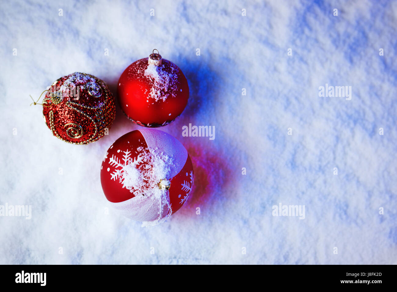 Verzierten Weihnachtskugeln im Schnee mit blauer Hintergrundbeleuchtung. Stockfoto
