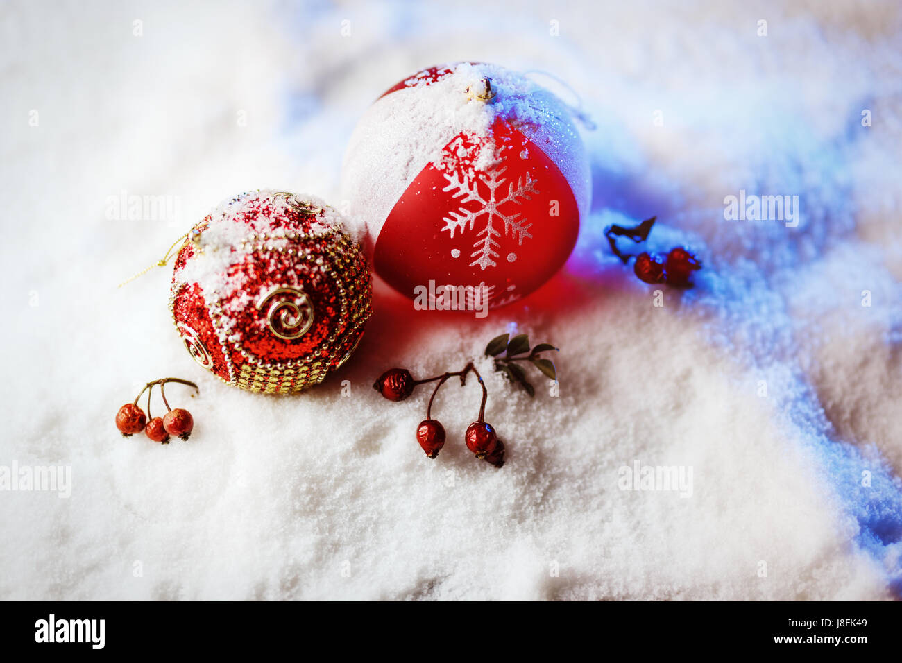 Verzierten Weihnachtskugeln im Schnee mit blauer Hintergrundbeleuchtung. Stockfoto