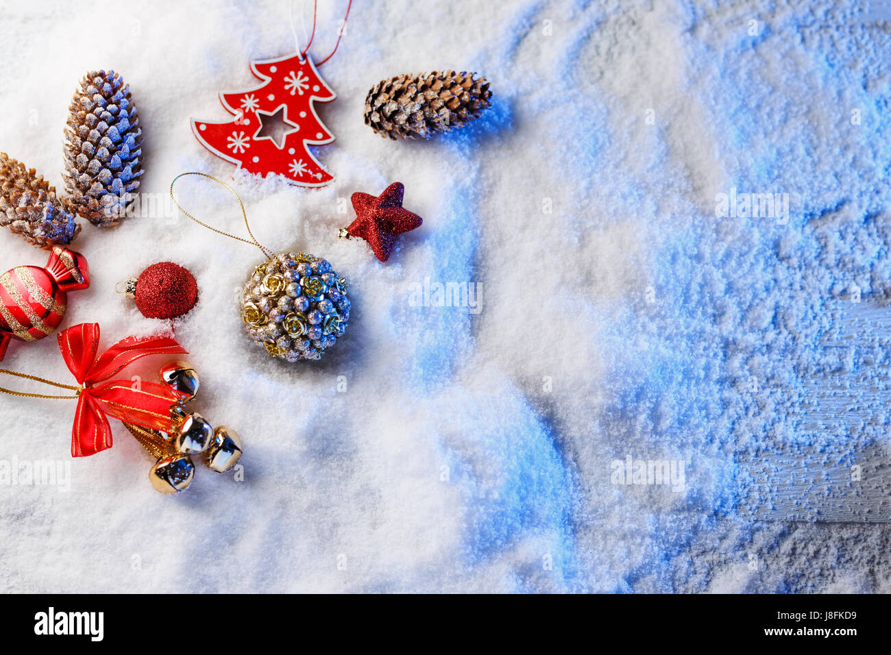 Weihnachtsschmuck im Schnee mit blauer Hintergrundbeleuchtung. Stockfoto
