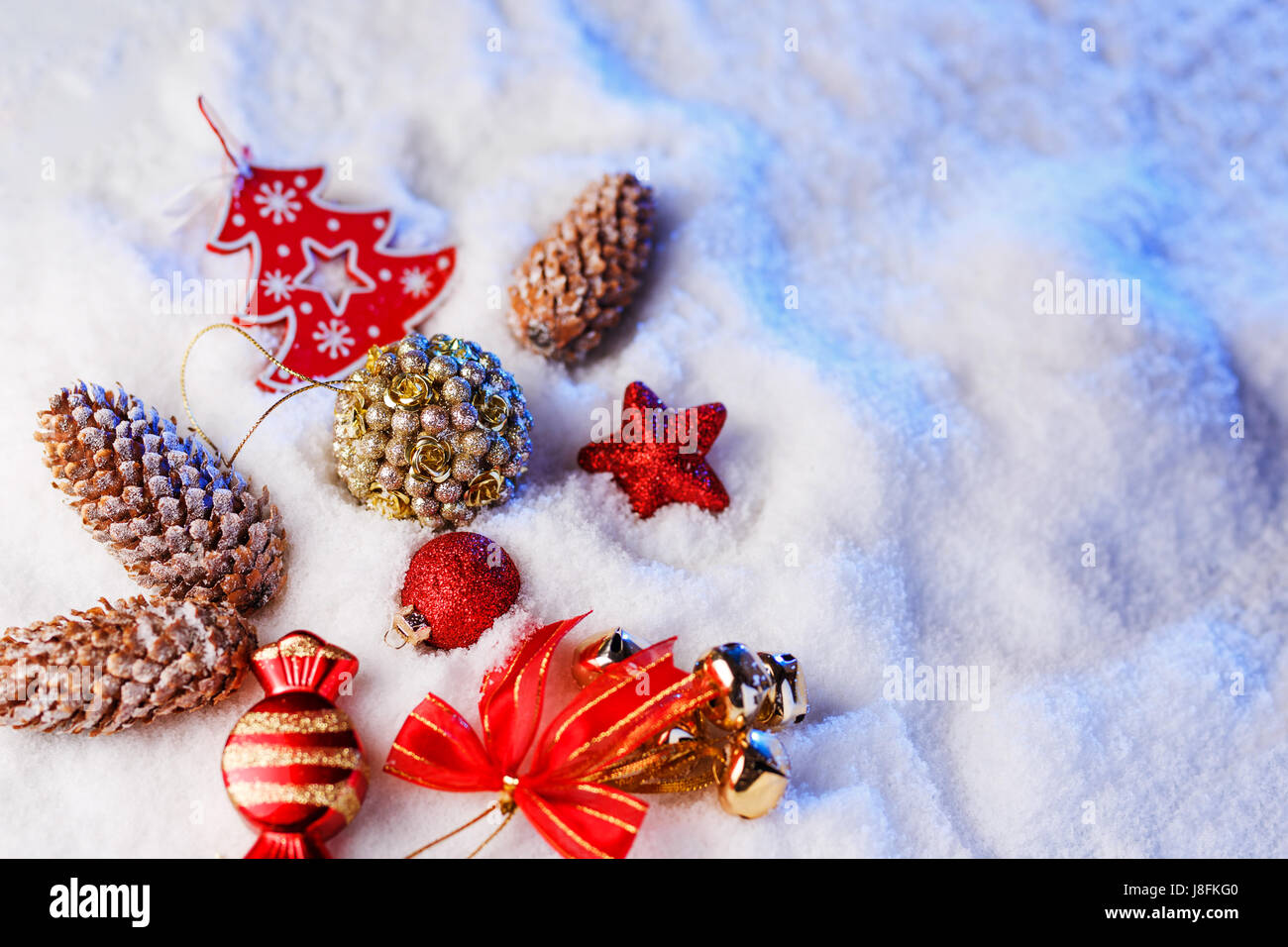 Weihnachtsschmuck im Schnee mit blauer Hintergrundbeleuchtung. Stockfoto