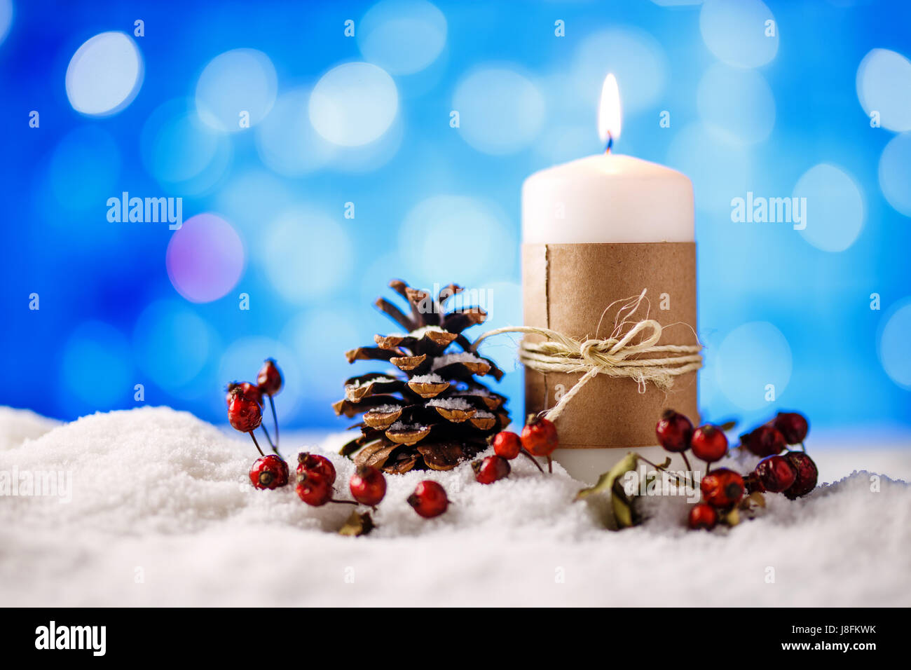 Kerze und Weihnachten Dekoration im Schnee mit blauem Licht Hintergrund. Stockfoto