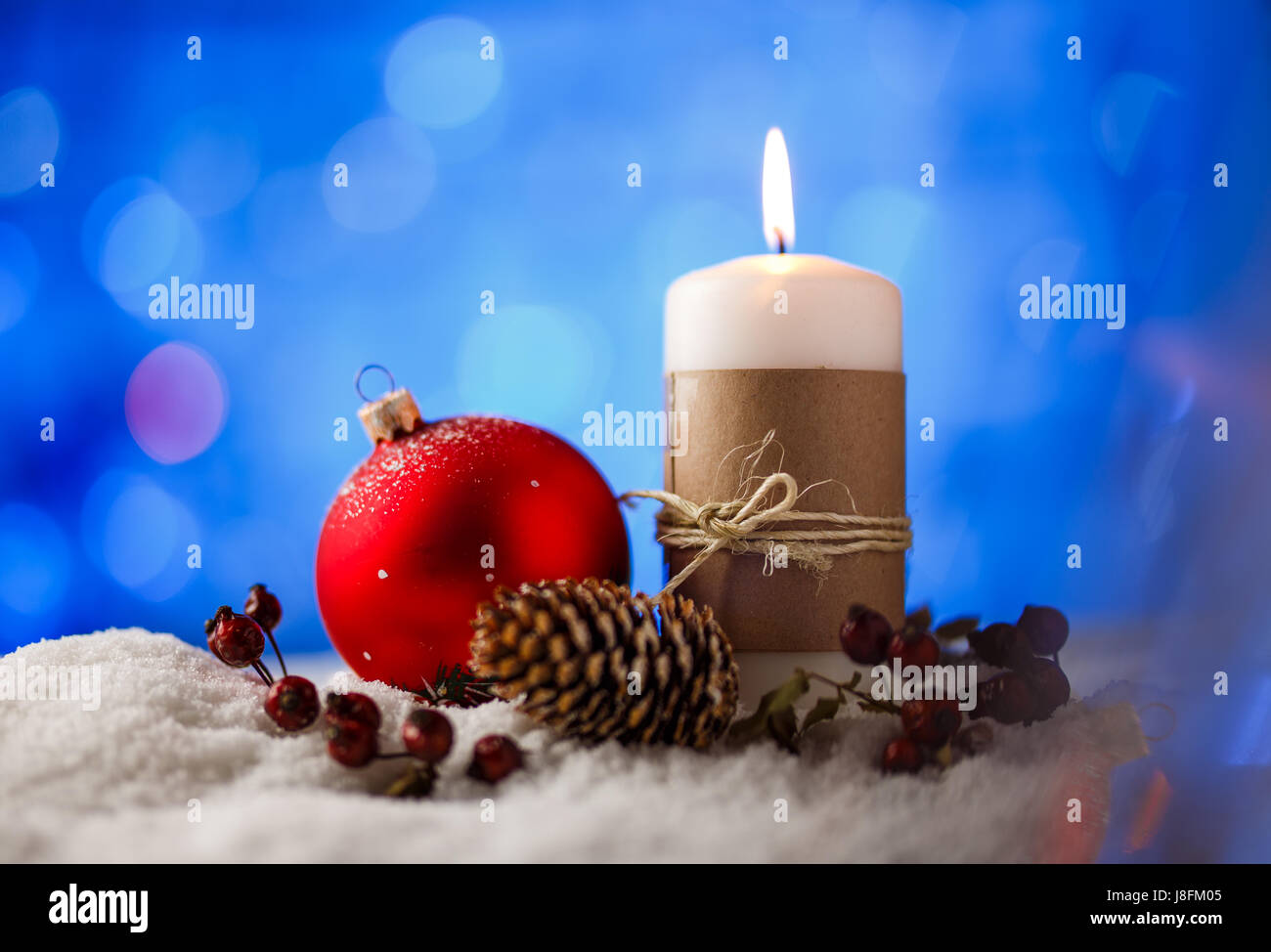 Kerze und Weihnachten Dekoration im Schnee mit blauem Licht Hintergrund. Stockfoto