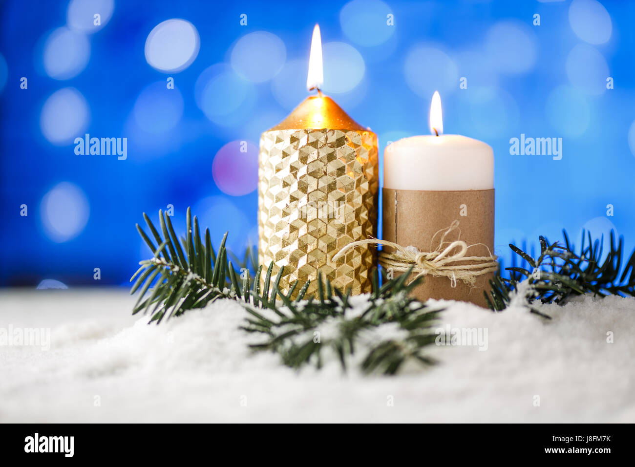 Kerze und Weihnachten Dekoration im Schnee mit blauem Licht Hintergrund. Stockfoto