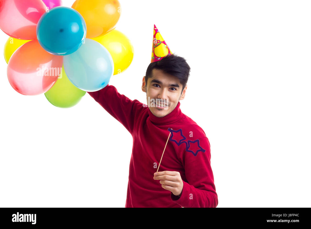 Positiven Jüngling im roten Hemd mit Hut hält viele bunten Luftballons und Karte-Stick Gläser auf weißem Hintergrund im Studio zu feiern Stockfoto