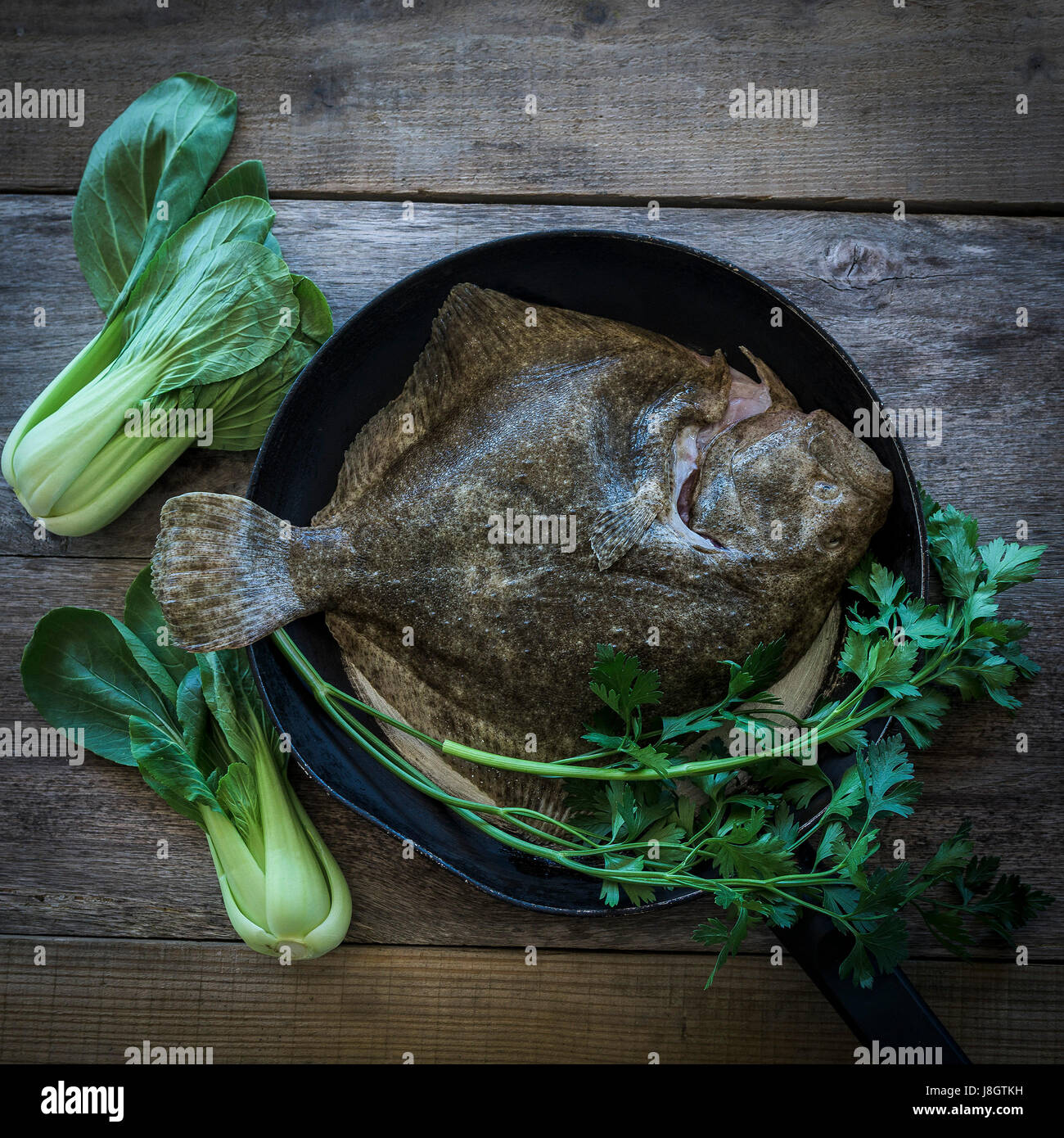 Ein Steinbutt, umgeben von jungem Gemüse; Essen; Fisch; Meeresfrüchte; Plattfische; Zutaten für eine Mahlzeit; Ungekocht; RAW; Gesunde Ernährung; Fischgericht Stockfoto