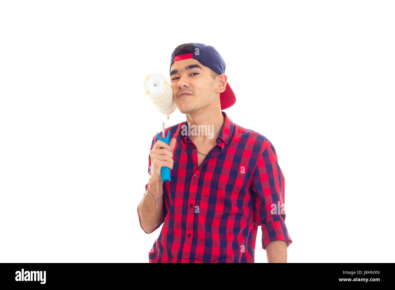 Junger lustige Mann mit dunklen Haaren in Rot kariertes Hemd mit blauen Snapback halten weiße Rollen auf weißem Hintergrund im studio Stockfoto