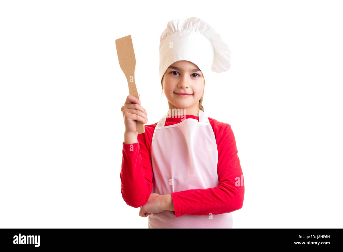 Schöne Mädchen im roten Hemd mit weißer Schürze und Hut hält Küche Spachtel auf weißem Hintergrund im studio Stockfoto