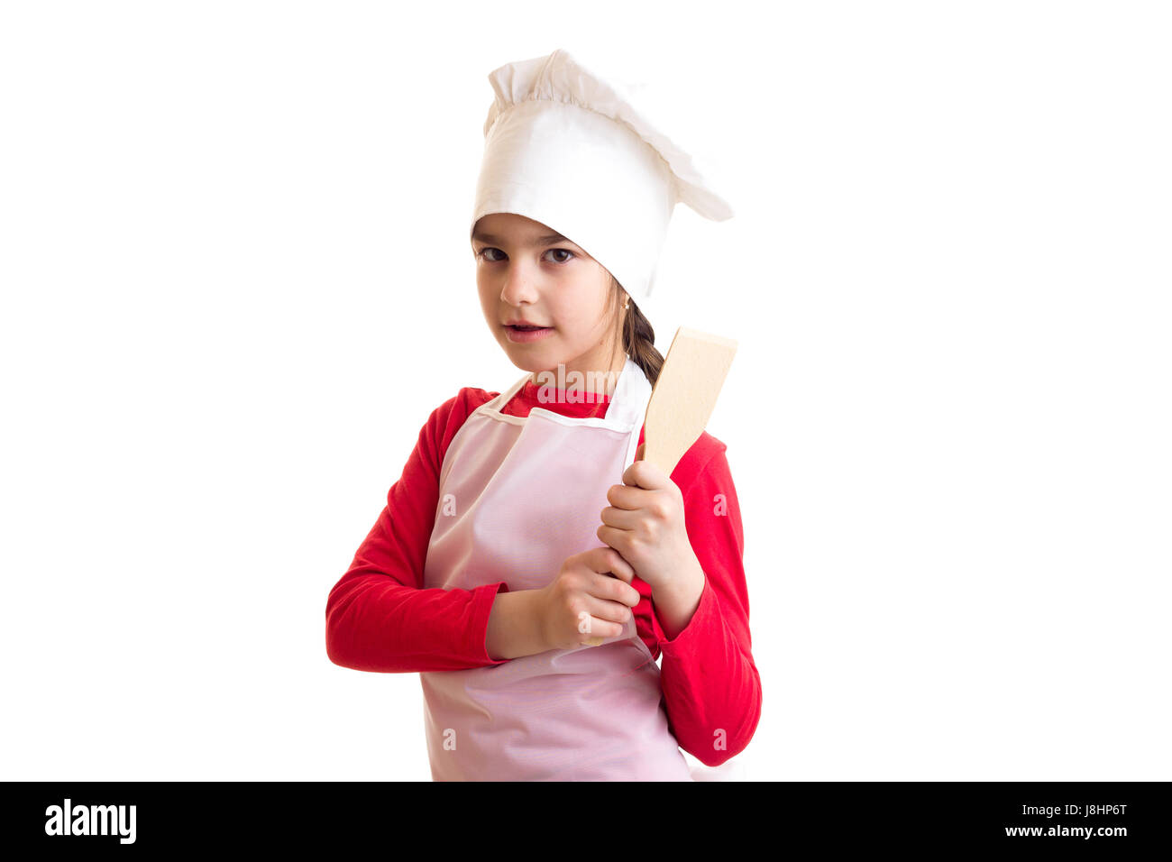 Schöne Mädchen im roten Hemd mit weißer Schürze und Hut hält Küche Spachtel auf weißem Hintergrund im studio Stockfoto