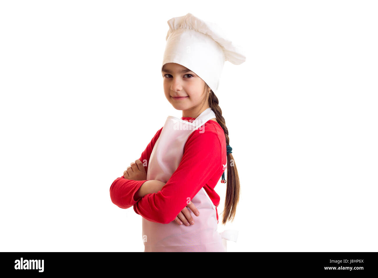 Kleines hübsches Mädchen tragen im roten Hemd mit weißer Schürze und des Herdes Hut auf weißem Hintergrund im studio Stockfoto