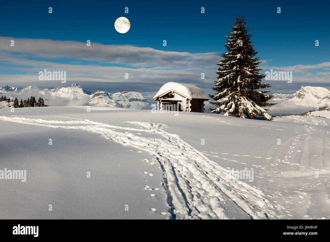 Vollmond über kleine Hütte und Tanne auf der Bergspitze in Megeve, Französische Alpen Stockfoto