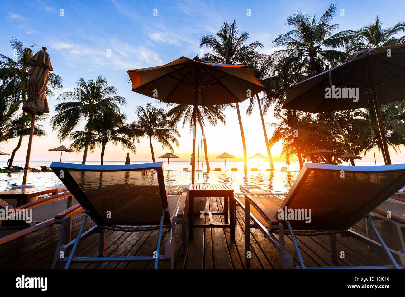 Wunderschönen tropischen Strand Ziel Landschaft mit luxuriösen Swimmingpool und Kokosnuss Palmen am Meer bei Sonnenuntergang Stockfoto