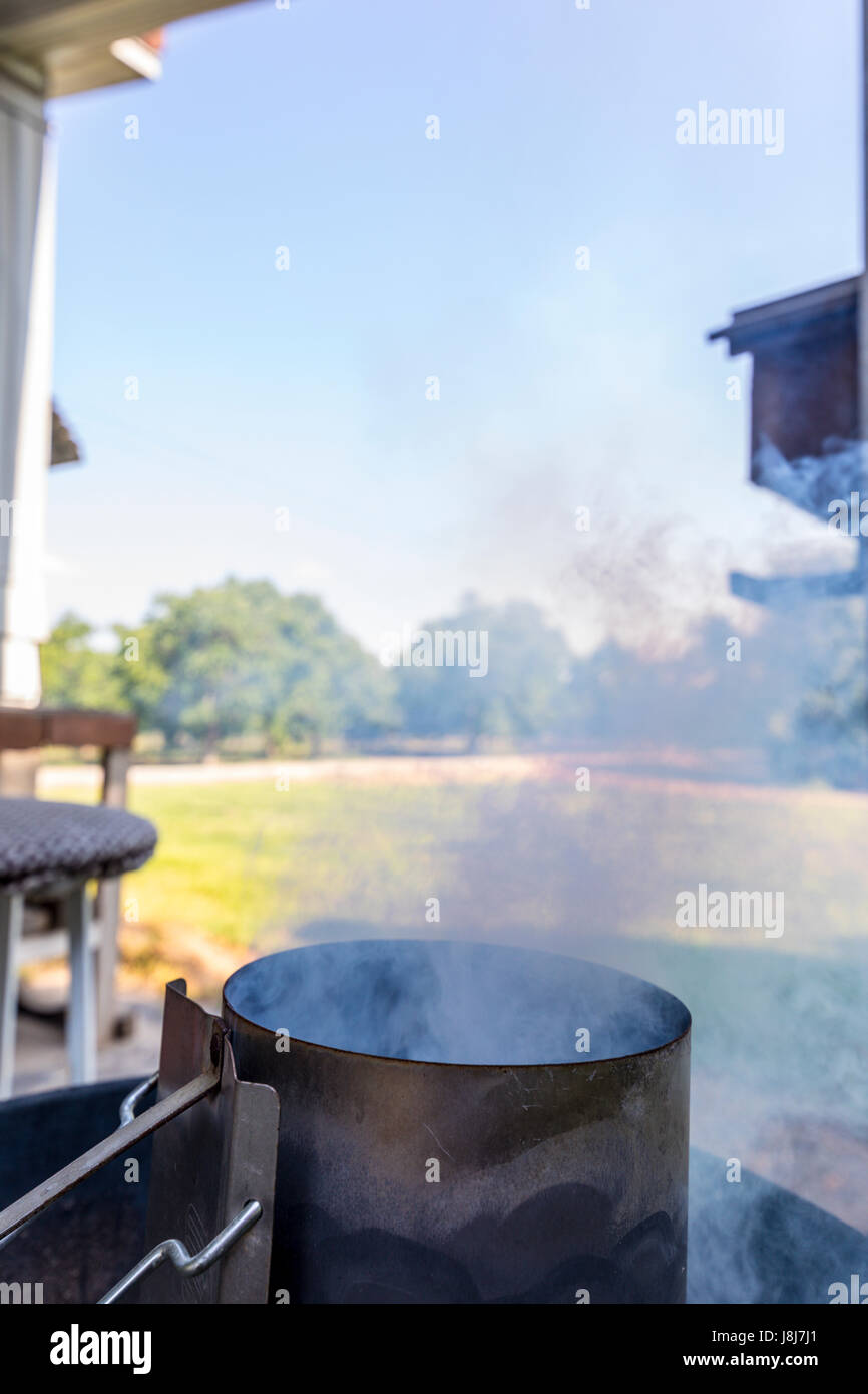 Ein Schornstein Stil Holzkohle Starter auf einem Weber Kettle Grill Stockfoto