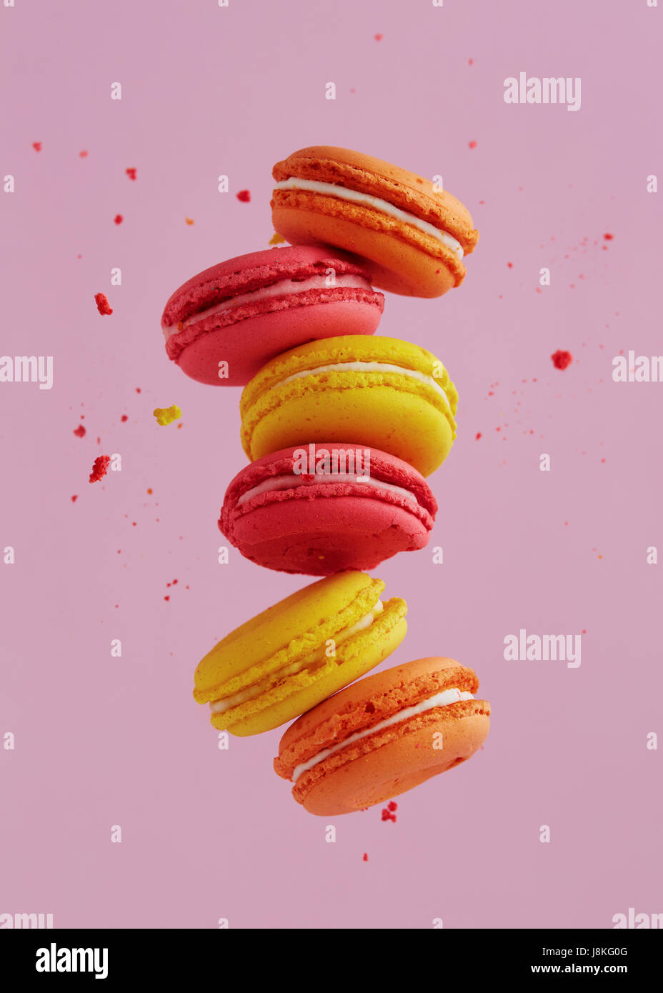 Verschiedene Arten von Makronen in Bewegung fallen auf rosa Hintergrund. Süße und bunte französische Macarons fallen oder fliegen in Bewegung. Stockfoto