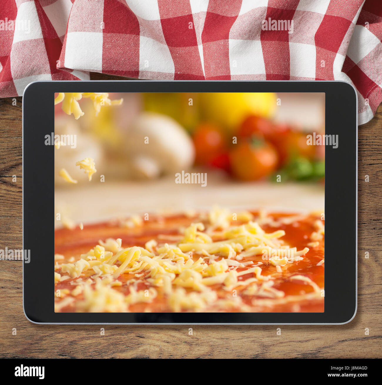 Schwarz Tablet-pc mit Pizza auf hölzernen Tisch und Picknick Tischdecke angezeigt Stockfoto