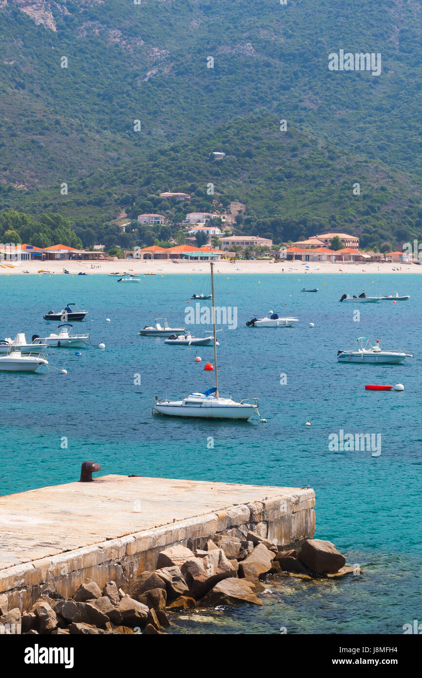 Freude Motorboote und Segelyachten verankert im Azure Bucht in der Nähe von Sandstrand des bergigen mediterranen Insel Corsica Stockfoto