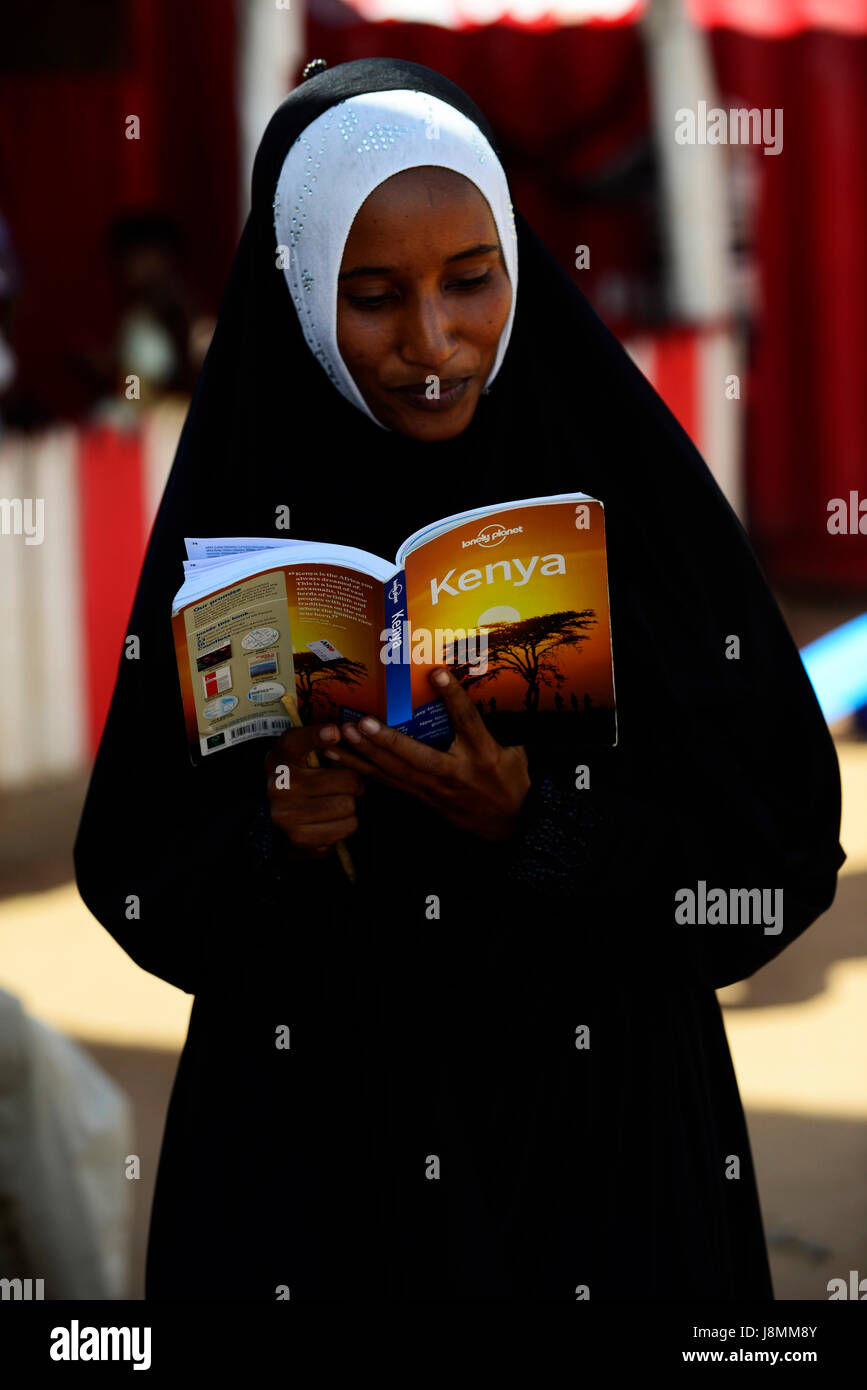 Eine junge kenianische Frau genießen lesen Der Lonely Planet Reiseführer zu Kenia. Stockfoto