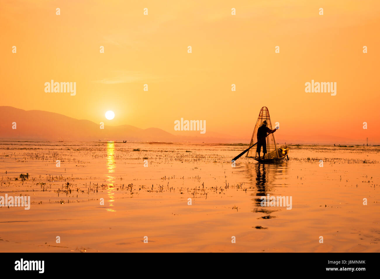 Silhouette eines burmesischen Fischers auf Bambus-Boot bei Sonnenuntergang. Inle-See, Myanmar (Burma), Reiseziel Stockfoto