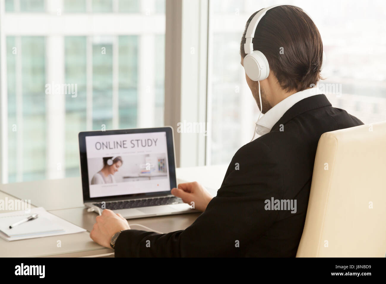 Mann im Kopfhörer am Laptop mit Online-Studie-Service-Web-Seite auf dem Bildschirm. Büroangestellter wählt frei Online-Qualifikation Kurs, improvin Stockfoto