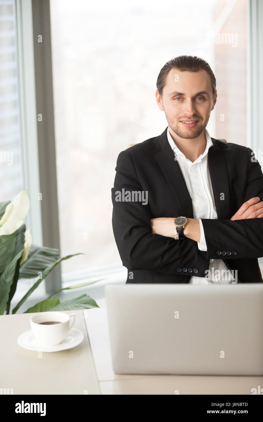 Porträt von CEO mit verschränkten Armen am Schreibtisch sitzen Stockfoto