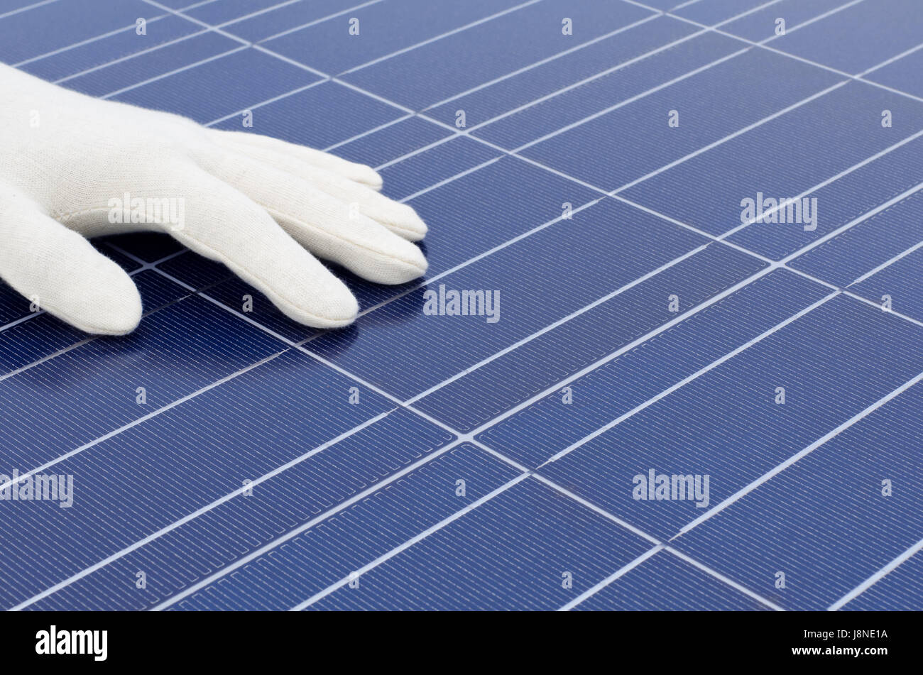Hand mit weißen Handschuhen vor Solarzellen Stockfoto