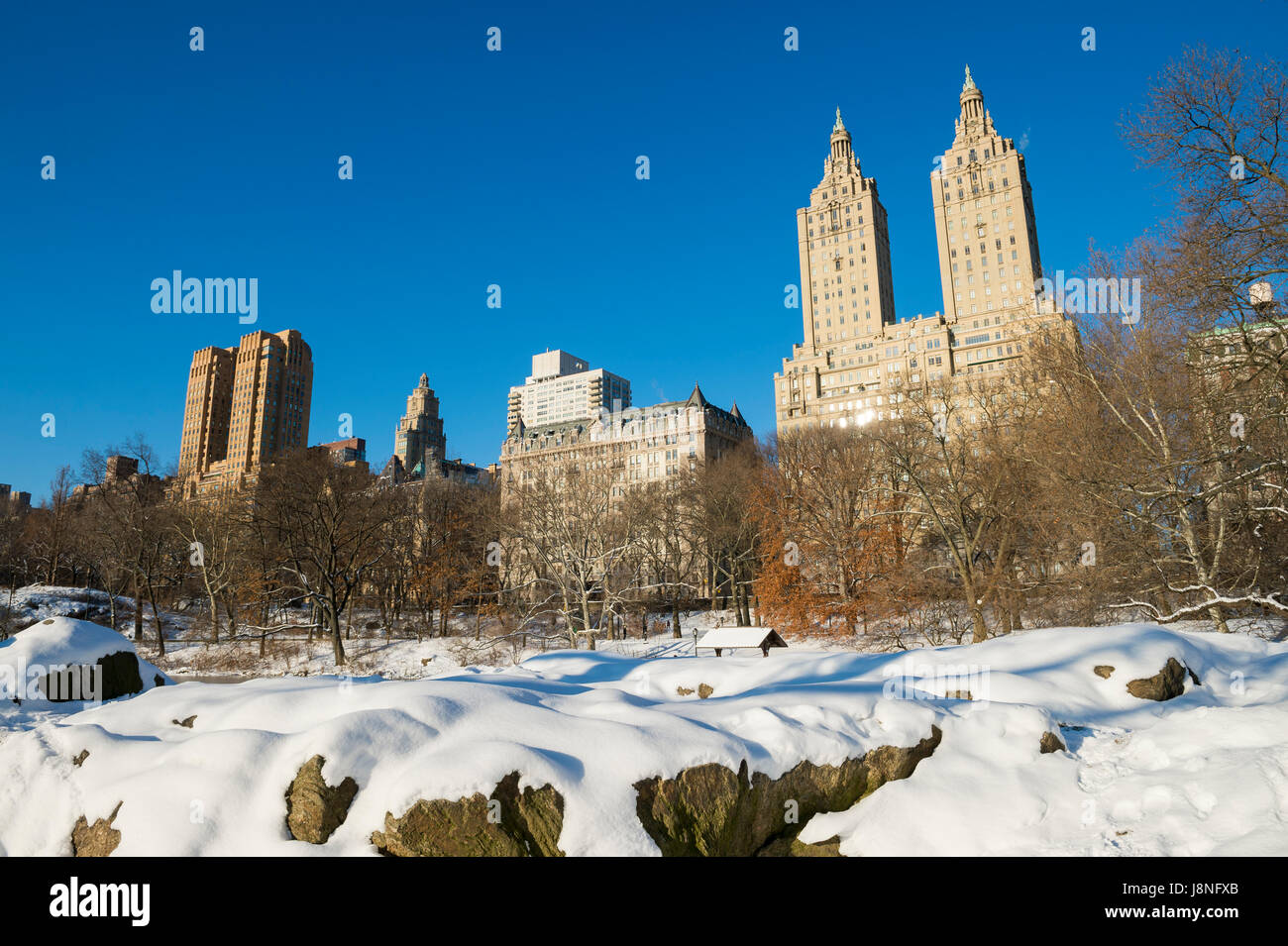 Malerische Aussicht auf die Skyline der Upper West Side von der Felskante des Central Park Sees am Morgen nach einem Winter Schneesturm in New York City Stockfoto