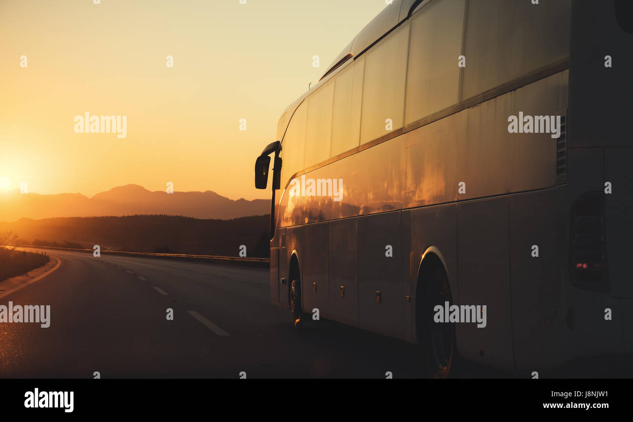 Weißer Bus fahren auf der Straße in Richtung der untergehenden Sonne Stockfoto